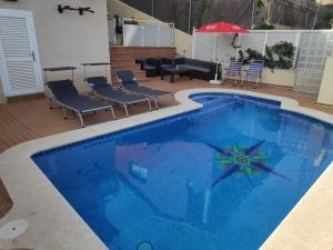 a large blue swimming pool with chairs and an umbrella at BEACH HOUSE. CASA CON PISCINA PRIVADA in Calafell