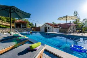 a swimming pool with chairs and an umbrella at Villa Mlin in Gruda