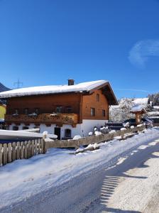 a snow covered building with a fence in front of it at Apartment Ferienhaus Seidlgut in Wagrain