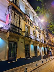a yellow building with balconies on a street at night at Hotel Simon in Seville