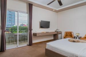 a bedroom with a bed and a tv and a balcony at Anik Boutique Hotel & Spa on Norodom Blvd in Phnom Penh