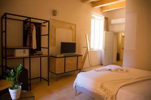 a bedroom with a bed and a television and a window at Locanda Carra Manna in Sassari