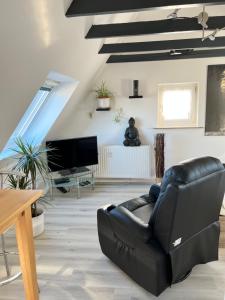 a living room with a black leather couch and a television at Waldblick in Herford