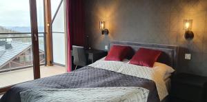 een slaapkamer met een bed met 2 rode kussens bij Karpatia Resort Apartament Karbonado in Karpacz