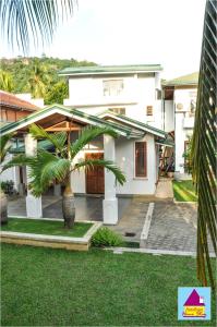 a white house with a palm tree in front of it at Surathura homestay in Kurunegala
