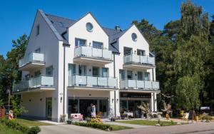 a large white building with people standing outside of it at Ava Apartamenty in Niechorze