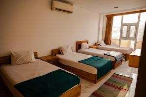 um quarto com três camas e uma janela em Station House em Dahab