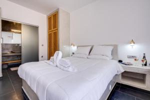 1 dormitorio con 1 cama blanca grande y toallas. en Beach Houses Santorini en Kamari