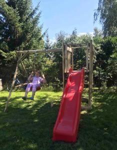a girl swinging on a slide on a playground at „ Lawendowy zakątek”/„Lavender cottage” in Żywiec in Żywiec +1 photo