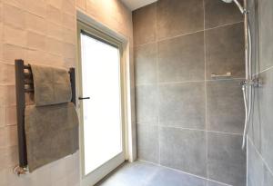 een badkamer met een douche en een glazen deur bij Uilengeluk in Veere