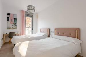 a bedroom with two beds and a desk and a window at Carmela Suites Apartamento de dos dormitorios in Granada