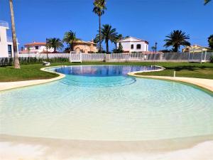 una grande piscina d'acqua in un cortile con palme di Denia Beach - Ático en Primera Línea by Costablancarent Rentals a Denia
