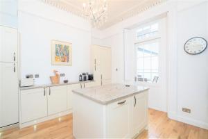 uma cozinha com armários brancos e um relógio na parede em 39 Rodney House em Cheltenham