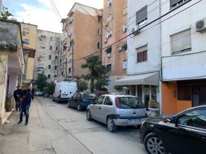 una persona caminando por una calle con coches aparcados en Guest House De Rada en Tirana