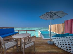 a patio with a table and chairs and an umbrella at Cora Cora Maldives - Premium All-Inclusive Resort in Raa Atoll