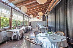 a restaurant with white tables and chairs and windows at Acta Arthotel in Andorra la Vella