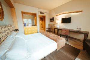 a bedroom with a large white bed and a desk at Barceló León Conde Luna in León +107 photos