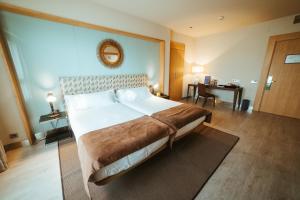 a hotel room with a large bed and a desk at Barceló León Conde Luna in León