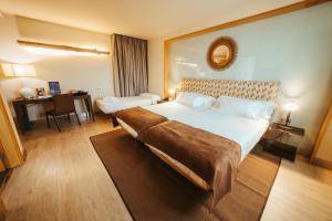 a hotel room with a large bed and a mirror at Barceló León Conde Luna in León