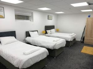 um quarto com três camas com lençóis brancos em Huge studio close to city centre with free secure parking em Leeds