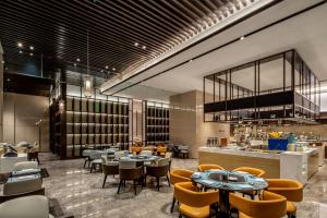 a restaurant with tables and chairs and a bar at Pullman Suzhou Taicang in Taicang