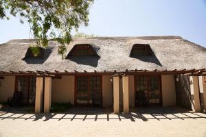 an old building with a thatched roof and windows at Oranjerus Resort in Kanoneiland