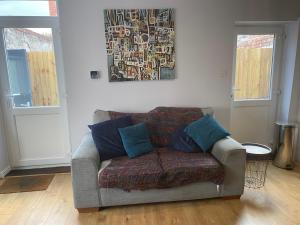 a couch in a living room with a painting on the wall at Lovely Coach House with Free Parking in Cardiff