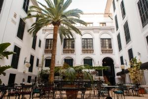 a palm tree in front of a building with tables and chairs at Hotel Born in Palma de Mallorca