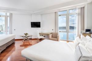 a white hotel room with a bed and a desk at Melia Maria Pita in A Coruña