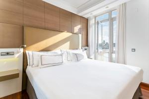 1 dormitorio con 1 cama blanca grande y ventana en Melia Maria Pita, en A Coruña
