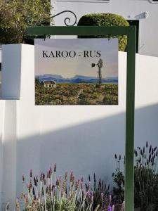 een teken voor Karao scheurt op een witte muur met bloemen bij Karoo-rus in Montagu