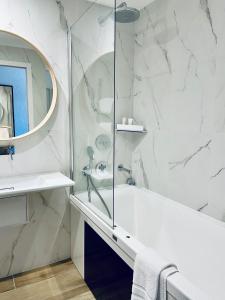 a white bathroom with a tub and a mirror at Hôtel Restaurant Le Clos Fleuri in Castelnaudary