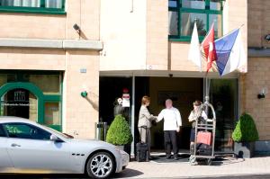 eine Gruppe von Personen, die vor einem Gebäude mit einer Flagge stehen in der Unterkunft Hotel Conti Dietikon in Dietikon