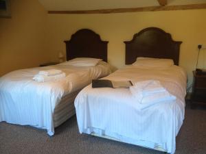 two beds in a room with white sheets and towels at Warmans Barn in Stansted Mountfitchet