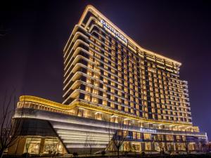 un edificio alto con luces encendidas por la noche en Pullman Suzhou Taicang en Taicang