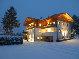 un grand bâtiment dans la neige la nuit dans l'établissement Jausenstation Moar, à Funes