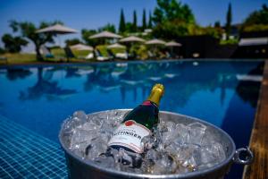 Una botella de champán en un cubo de hielo junto a una piscina en Herdade da Cortesia Hotel, en Avis