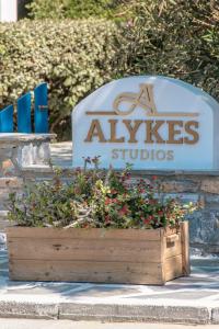 a sign for studios with flowers in a wooden box at Alykes Studios & Suites in Agios Prokopios