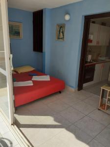 um quarto com uma cama vermelha e uma cozinha em Josip 2 Gajac em Novalja