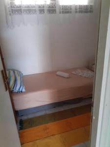 a small bed in a room with a window at Josip 2 Gajac in Novalja