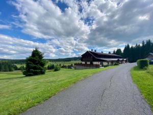 eine Straße, die zu einem Haus auf einem Grasfeld führt in der Unterkunft Pension Hones in Horská Kvilda