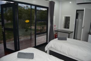 Habitación con 2 camas y una gran ventana de cristal. en SleepOver Orpen Gate en Acornhoek