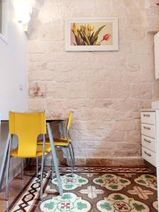 duas cadeiras amarelas e uma mesa num quarto em Apartment Mammacara em Ceglie Messapica