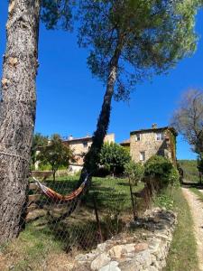a hammock between two trees in front of a house at Domaine Le Petit Hameau in Cotignac