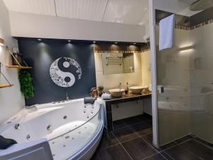 a bathroom with a large bath tub and a sink at Chambres d'Hôtes La Filature in Saint-Quentin