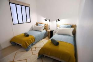 2 Betten in einem Zimmer mit Gelb- und Blautönen in der Unterkunft Le Thiou 3 étoiles - Charmant & Authentique, Au Cœur de la Vieille Ville, Billard, 6 personnes in Annecy
