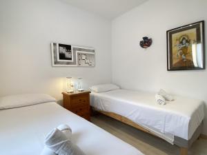 dwa łóżka w pokoju z białymi ścianami w obiekcie Penthouse Clavero Casasol w mieście Nerja