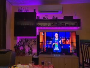 człowiek stojący na telewizorze w pokoju z fioletowymi światłami w obiekcie Koko's apartments 2 w mieście Bansko