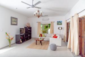 a living room with a couch and a ceiling fan at Riverside Mount Simpson - Seychelles Island in Mahe