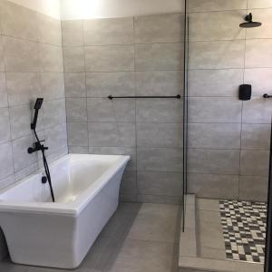 a white bath tub in a bathroom with a shower at 11 On Grace in East London